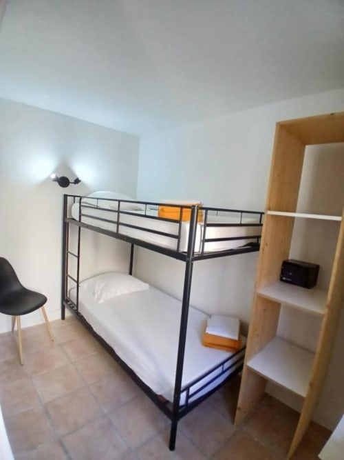 Modern bunk bed in family room at Hôtel Quai d'Azur, Le Grau-du-Roi with wooden shelving and black chair