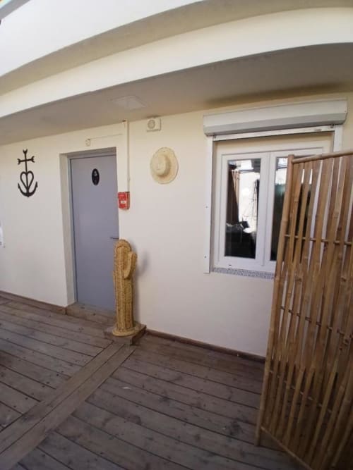 Hôtel Quai d'Azur ground floor family room entry with blue door, straw hat, wooden gate and nautical decor in Le Grau-du-Roi
