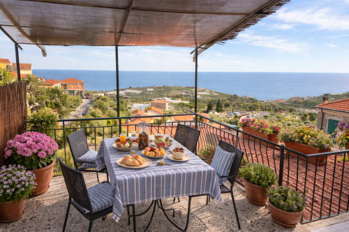 Terrazza a bordo mare presso l'Agriturismo Il Vecchio Mulino, con tavoli a strisce, dolci freschi e vista sul Mediterraneo