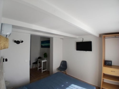 Modern hotel room at Hôtel Quai d'Azur with bed, TV, desk area, and wooden furniture in Le Grau-du-Roi