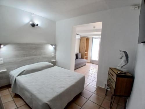 Hôtel Quai d'Azur double room with bed, wooden dresser, and doorway to seating area in Le Grau-du-Roi