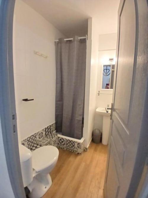 Modern bathroom at Hôtel Quai d'Azur with shower, toilet, sink, and wooden flooring in Le Grau-du-Roi