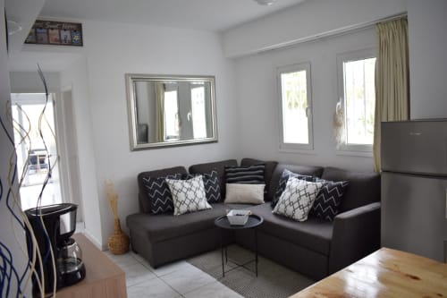 Modern apartment living room in Costa Adeje with black corner sofa, decorative pillows, large mirror, and balcony doors