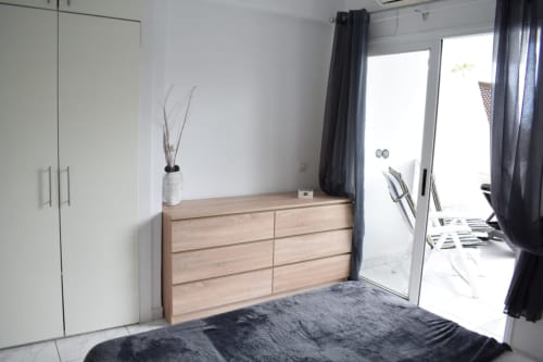 Modern apartment bedroom in Costa Adeje with wooden dresser, white wardrobe, and terrace access