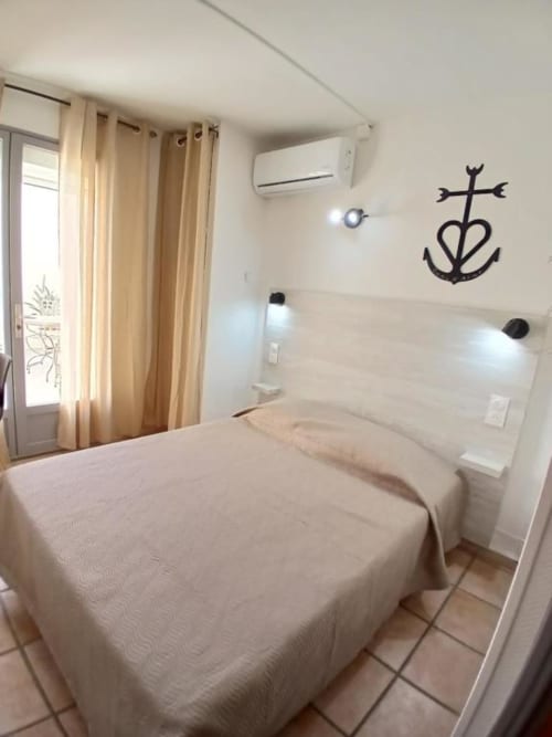 Bright double bedroom at Hôtel Quai d'Azur in Le Grau-du-Roi with white bedding, modern amenities, and nautical décor