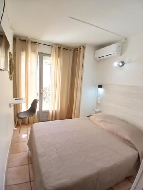 Bright double room at Hôtel Quai d'Azur with bed, desk, air conditioning, and balcony doors in Le Grau-du-Roi