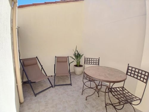 Sunny terrace at Hôtel Quai d'Azur Le Grau-du-Roi with deck chairs, dining table, and potted plant