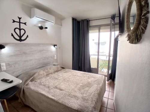 Modern double bedroom at Hôtel Quai d'Azur with balcony access, air conditioning, and nautical décor in Le Grau-du-Roi