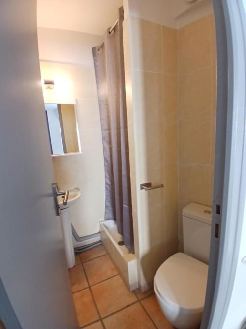Modern hotel bathroom at Hôtel Quai d'Azur with toilet, shower, and vanity mirror in Le Grau-du-Roi