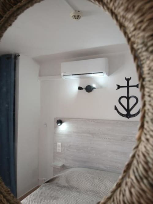 Bathroom mirror view at Hôtel Quai d'Azur Le Grau-du-Roi, showing modern fixtures and nautical anchor decoration