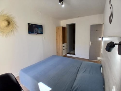 Modern double room at Hôtel Quai d'Azur in Le Grau-du-Roi with blue bed, wooden wardrobe, and ensuite bathroom