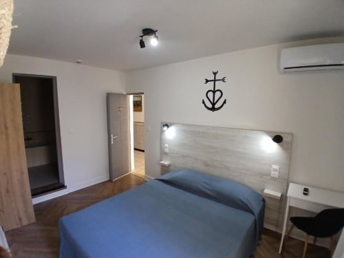 Modern double bedroom at Hôtel Quai d'Azur in Le Grau-du-Roi with blue bedding, wooden headboard, and nautical décor