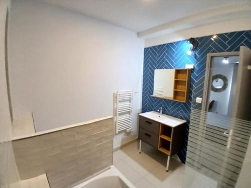 Modern bathroom at Hôtel Quai d'Azur with blue herringbone tiles, vanity sink, bathtub, and heated towel rack in Le