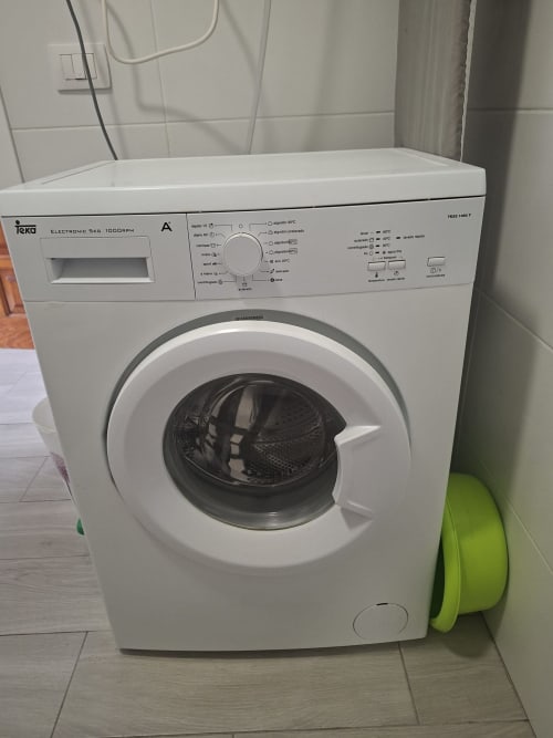 White Teka washing machine in Costa Adeje apartment with laundry basket nearby, showcasing in-unit laundry amenity