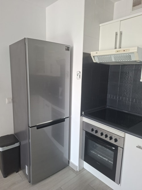Modern kitchen in Costa Adeje apartment featuring stainless steel refrigerator, electric cooker, range hood, and black