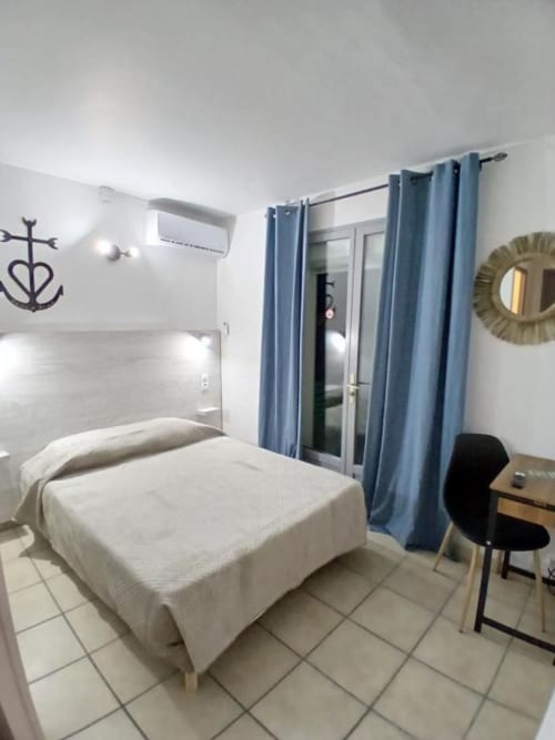 Modern bedroom at Hôtel Quai d'Azur with white bed, blue curtains, air conditioning, and workspace