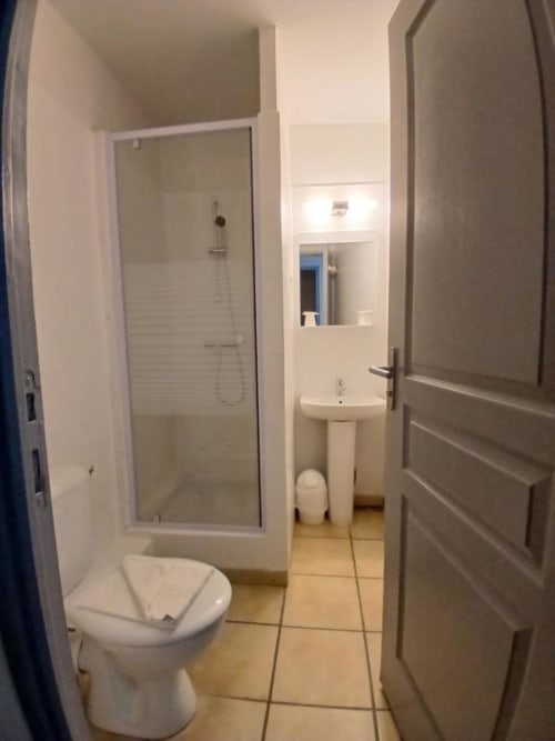 Modern bathroom at Hôtel Quai d'Azur with toilet, sink, and glass shower enclosure in Le Grau-du-Roi