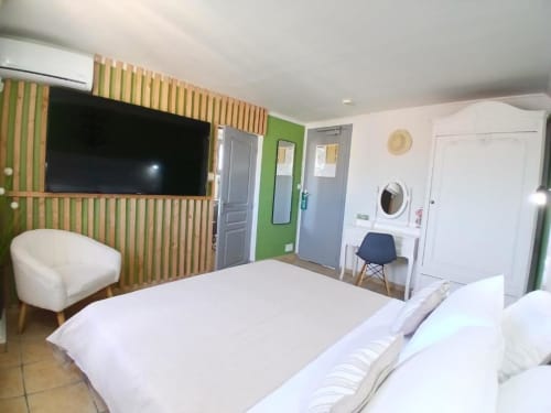 Modern hotel room at Hôtel Quai d'Azur with bed, green accent wall, wall-mounted TV, and ensuite amenities