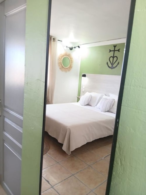Modern bedroom at Hôtel Quai d'Azur with green accent walls, white bedding, and decorative mirrors