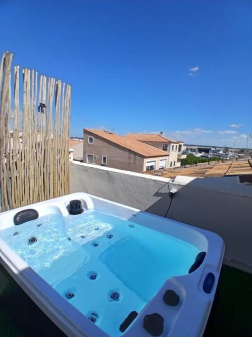 Rooftop hot tub at Hôtel Quai d'Azur in Le Grau-du-Roi with sea views and wooden privacy fence