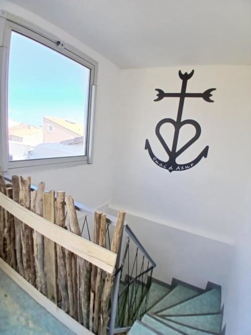 Stairwell at Hôtel Quai d'Azur with anchor-heart wall decal and coastal window view