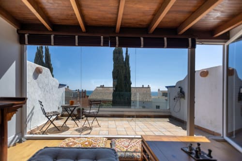 Soleada terraza en la azotea de BH Marbella con tumbonas, vistas de cipreses y arquitectura mediterránea con vistas al mar