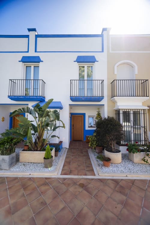 Patio del hotel BH Marbella con arquitectura mediterránea azul y blanca, balcones y plantas tropicales