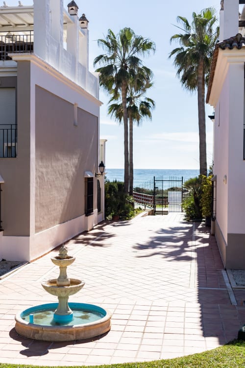 Paseo costero en BH Marbella con fuente, palmeras y vistas al Mar Mediterráneo