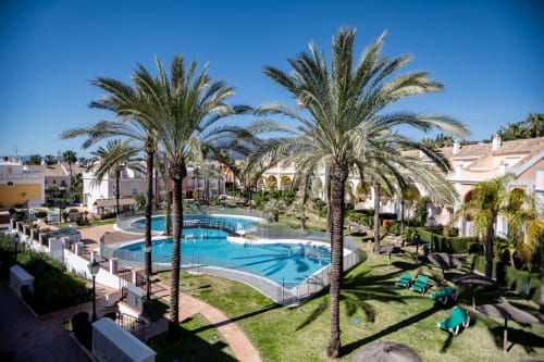 Piscina del hotel BH Marbella con palmeras, tumbonas y arquitectura mediterránea bajo el sol de Marbella