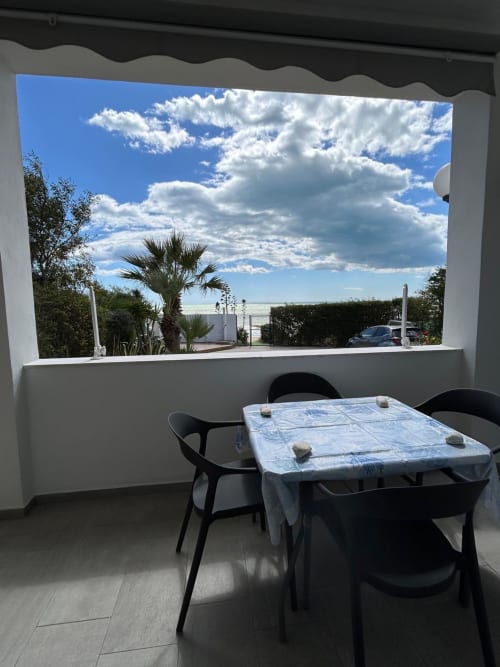Tavolo da pranzo con vista sul mare dall'appartamento Sostare a Gela, con palme e paesaggio costiero
