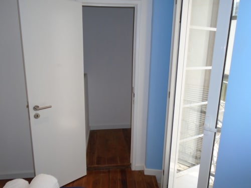 Corredor moderno de apartamento no Bairro Alto, Lisboa, com portas brancas, parede azul e soalho em madeira escura