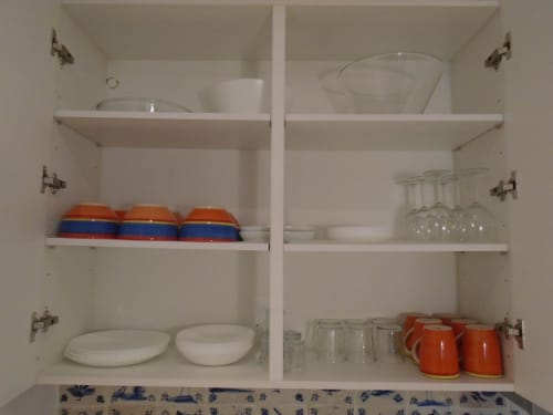 Cristaleira da cozinha com louça, copos e tigelas coloridas em apartamento em Lisboa