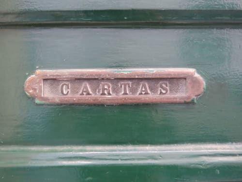 Caixa de correio vintage em cobre 'CARTAS' na porta de madeira verde de apartamento lisboeta no Bairro Alto
