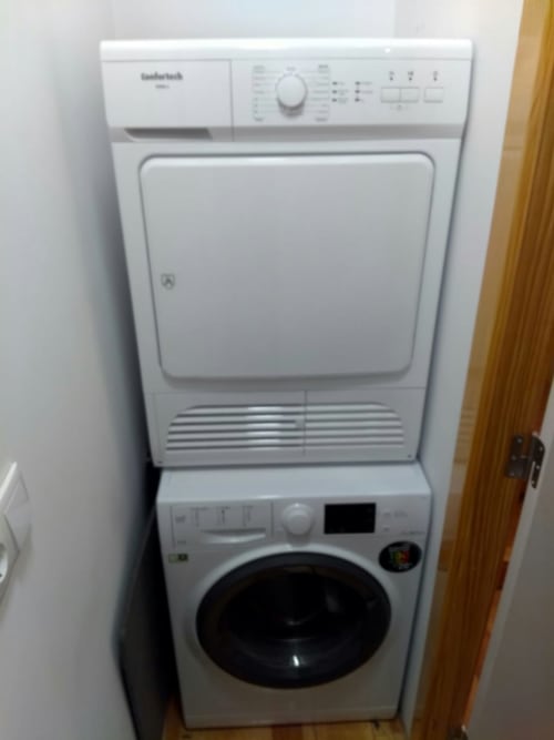 Unidade empilhada de máquina de lavar e secar Bauknecht branca na área de lavanderia do apartamento no Bairro Alto.