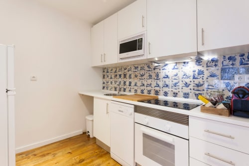 Cozinha moderna branca com azulejos azuis na bancada em apartamento no Bairro Alto de Lisboa
