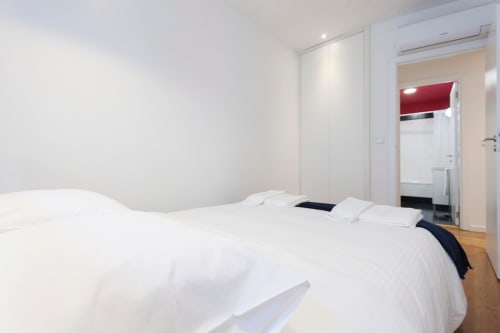Quarto moderno com roupa de cama branca na Lisbon Heart Pulse Stays, design minimalista e acesso a casa de banho privada.