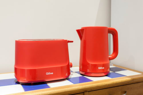 Chaleira e torradeira Qilive vermelhas sobre tapete xadrez na cozinha de apartamento em Lisboa