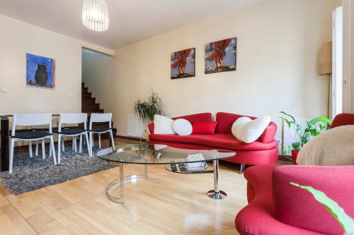 Sala de estar moderna em apartamento lisboeta com sofá vermelho, mesa de vidro, zona de refeições e decoração contemporânea