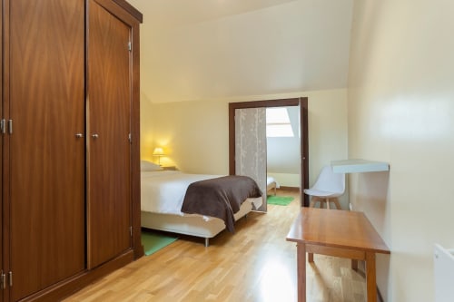 Espaçoso quarto de apartamento em Lisboa com guarda-roupa em madeira, cama, secretária e piso em madeira maciça