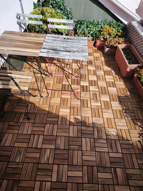 Terraço com deck de madeira, flores em vasos e mobiliário exterior no apartamento Lisbon Heart Pulse Stays