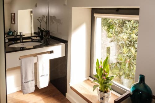 Banheiro moderno na Quinta de Anterronde com bancada preta, pia, espelho, toalheiro e planta em vaso junto à janela