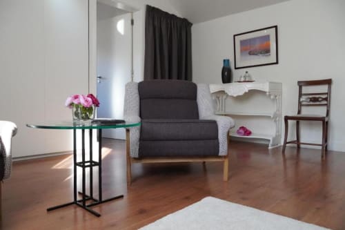 Quarto deluxe moderno na Quinta de Anterronde em Arouca com poltrona confortável, mesa de vidro, prateleiras brancas e acabamentos em madeira