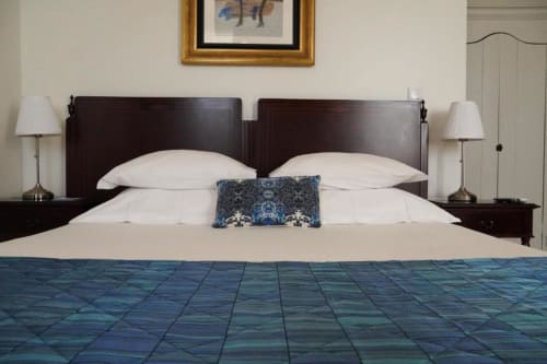Quarto triplo de luxo na Quinta de Anterronde em Arouca com cabeceira em madeira escura, almofadas brancas e roupa de cama azul estampada.