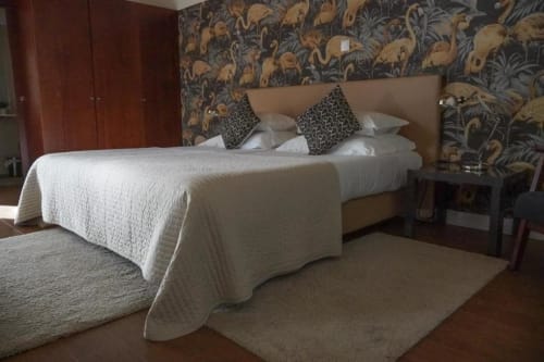 Espaçoso quarto familiar na Quinta de Anterronde em Arouca com cama estofada bege, roupa branca e papel de parede estampado