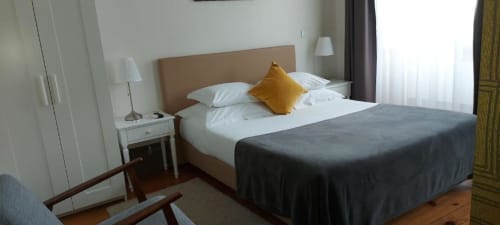 Quarto duplo padrão na Quinta de Anterronde com vista para a montanha, cabeceira bege, roupa de cama branca e almofada amarela