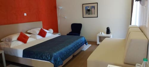Sala de estar luminosa na Quinta de Anterronde com cama queen, detalhes em vermelho, sofá, janela com vista para o jardim e comodidades modernas