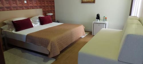 Suite Tripla Superior na Quinta de Anterronde com cama queen, almofadas bordô, sofá e vista para o jardim em Arouca