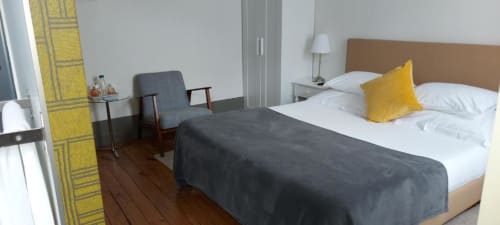 Quarto moderno na Quinta de Anterronde com cama de casal, almofada amarela, área de estar e piso em madeira em Arouca
