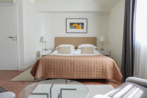 Quarto de luxo da Quinta de Anterronde com cama estofada em bege, criados-mudo brancos e vista para o jardim em Arouca, Portugal.