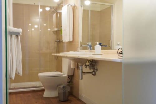 Casa de banho moderna no Quarto Deluxe Triple da Quinta de Anterronde, com box de vidro, lavatório branco, sanita e
